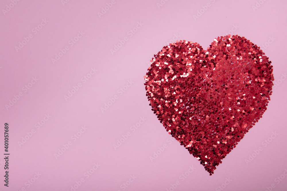 Heart shape made of red glitter on pink background. Love concept.