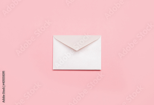 White mail envelope for letters on a pink background. Minimalist style, top view, correspondence concept.