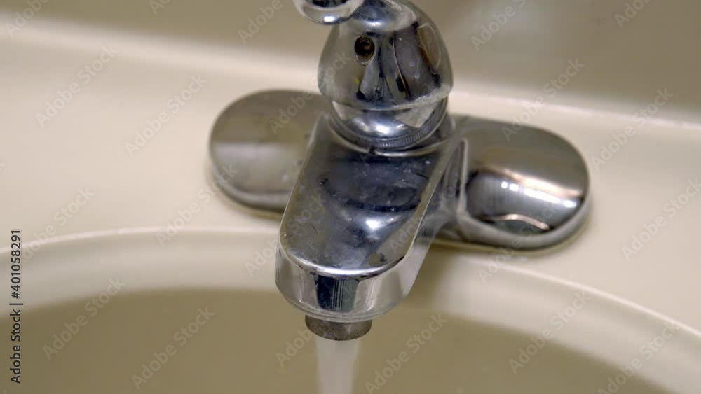 Tight close up of white hands using soap dispenser and washing under sink faucet in slow motion as bubbles drain Tight close up of white hands using soap dispenser and washing under sink faucet in slow motion as bubbles drain