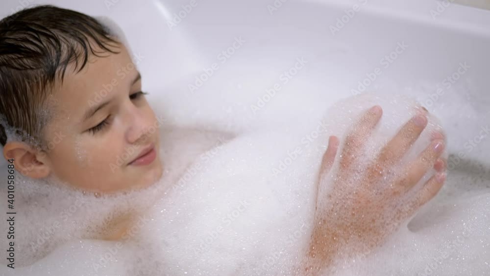 Boy Bathes in Bathroom with Foam, Plays with Bubbles of Soapy Foam, Happy Child Boy Bathes in Bathroom with Foam, Plays with Bubbles of Soapy Foam, Happy Child