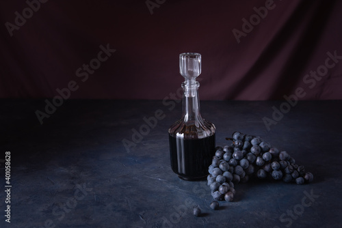 balsamic vinegar in a glass bottle with a bunch of grapes on a stone table