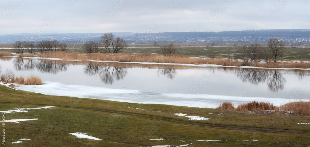 Spring panorama of a calm river. Melting ice on the river.