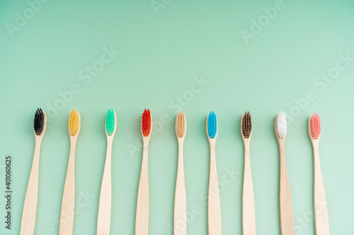 A set of Eco-friendly antibacterial toothbrushes made of bamboo wood on a light green background. Environmental care trends
