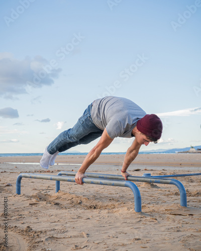 Fotografi Callisthenics on the beach on the parallel bars