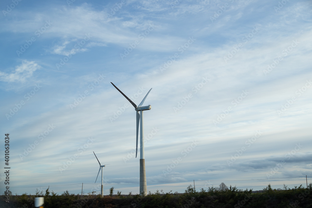 Wind turbine. Empty road in foreground, blue sky with clouds. Alternative energy source, production and power generation. Ecology and freedom concept. Wind turbine. Empty road in foreground, blue sky with clouds. Alternative energy source, production and power generation. Ecology and freedom concept.