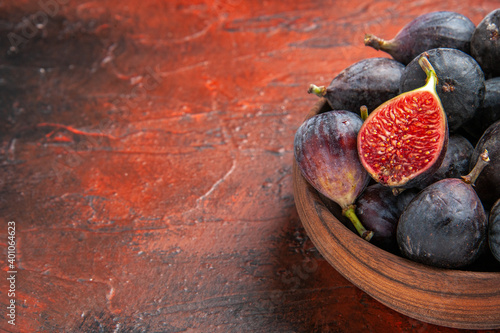 Half shot of full fresh black mission figs and split ones in a small brown pot on colorful background photo