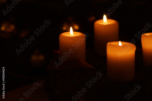 Close up of an advent wreath spending warn golden light in front of a christmas tree