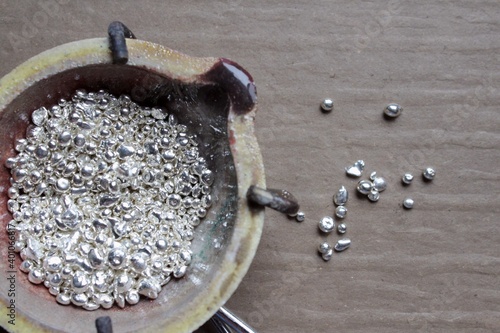 Fotografie A ceramic crucible or melting pot with grains of sterling silver 925 for jewelry making after hand smelting in a workshop