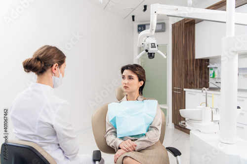 A young woman talking to her dentist in the dental clinic.