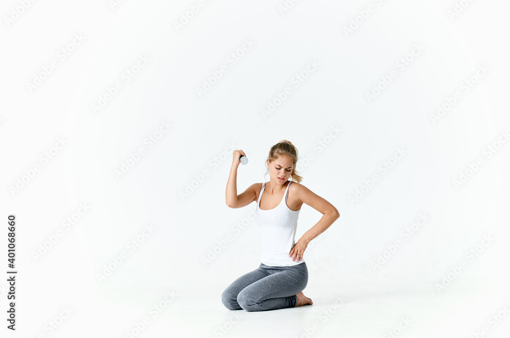Fototapeta premium woman with dumbbells and in sportswear sits on the floor in a bright room