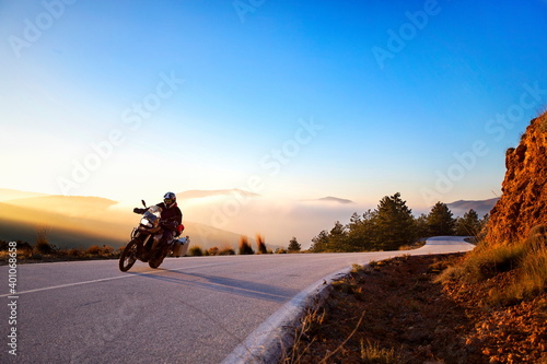 Obraz na płótnie A motorcyclist taking a beautiful curve in front of a magical sunset
