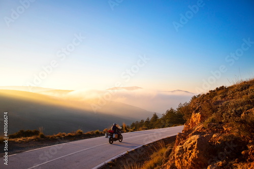 A motorcyclist taking a beautiful curve in front of a magical sunset. The sky, the trees, the motorcycle and the colors make this photo incredible. © Juanjo Albalá