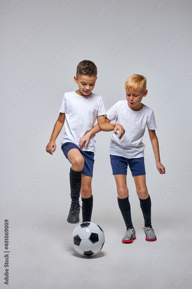 children soccer team on training, two boys practicing game with a soccer ball in studio. training football session for children on soccer camp. young boy improving dribbling skills children soccer team on training, two boys practicing game with a soccer ball in studio. training football session for children on soccer camp. young boy improving dribbling skills