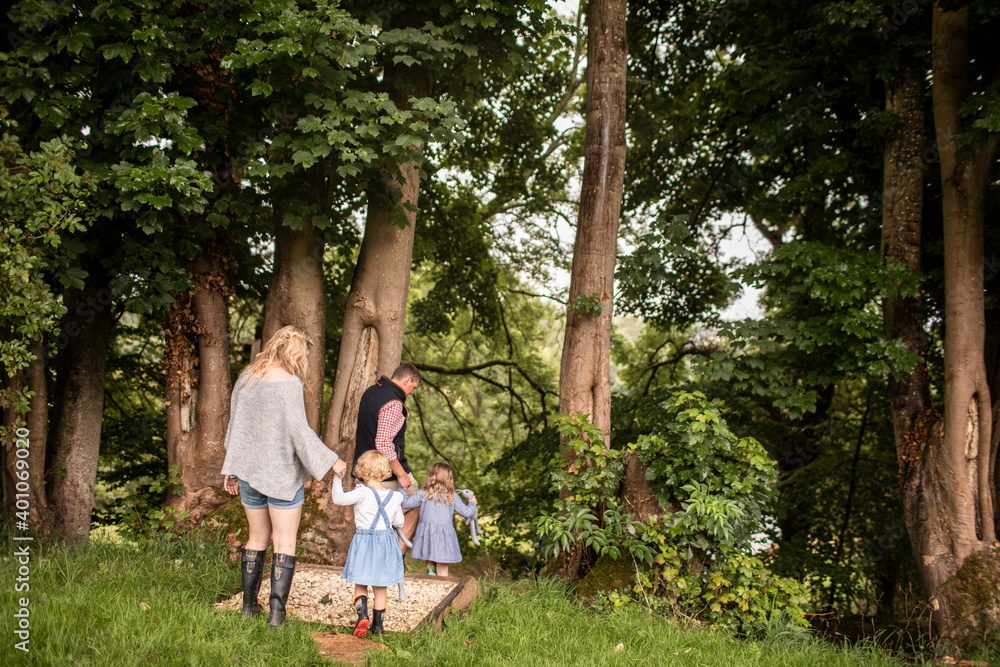 Family holding hands walking among trees on path in woods Family holding hands walking among trees on path in woods