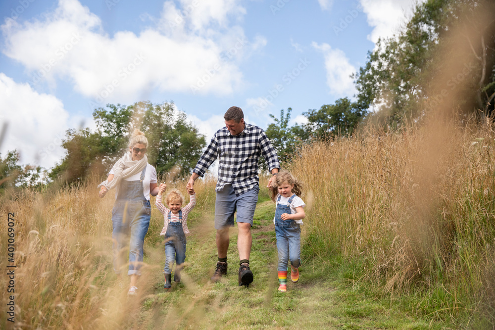 Happy family holding hands running in sunny rural field Happy family holding hands running in sunny rural field