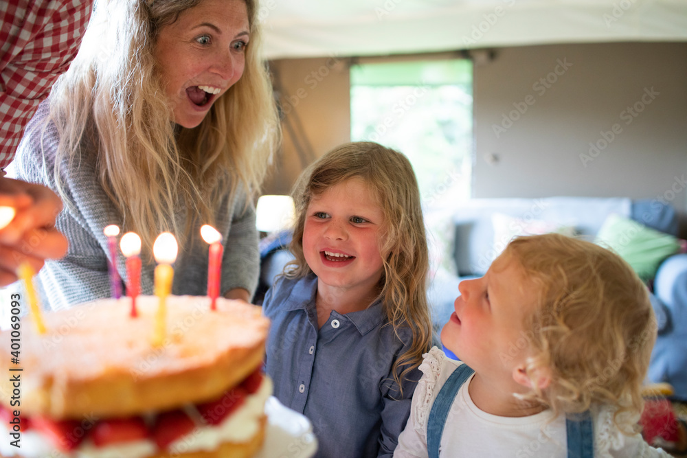 Happy mother and daughters celebrating birthday with cake and candles Happy mother and daughters celebrating birthday with cake and candles