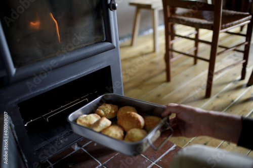 Man placing biscuits into stove oven in cabin
