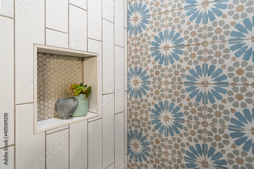 Detail of flower pattern tile shower inset with heart and plant decor.