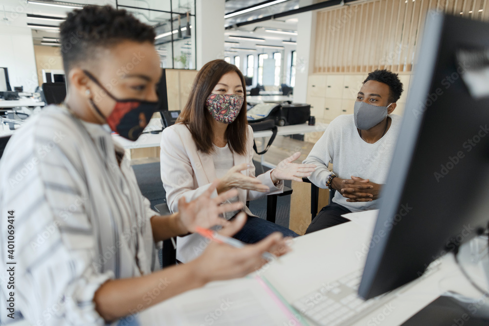 Business people in face masks video conferencing at office computer Business people in face masks video conferencing at office computer