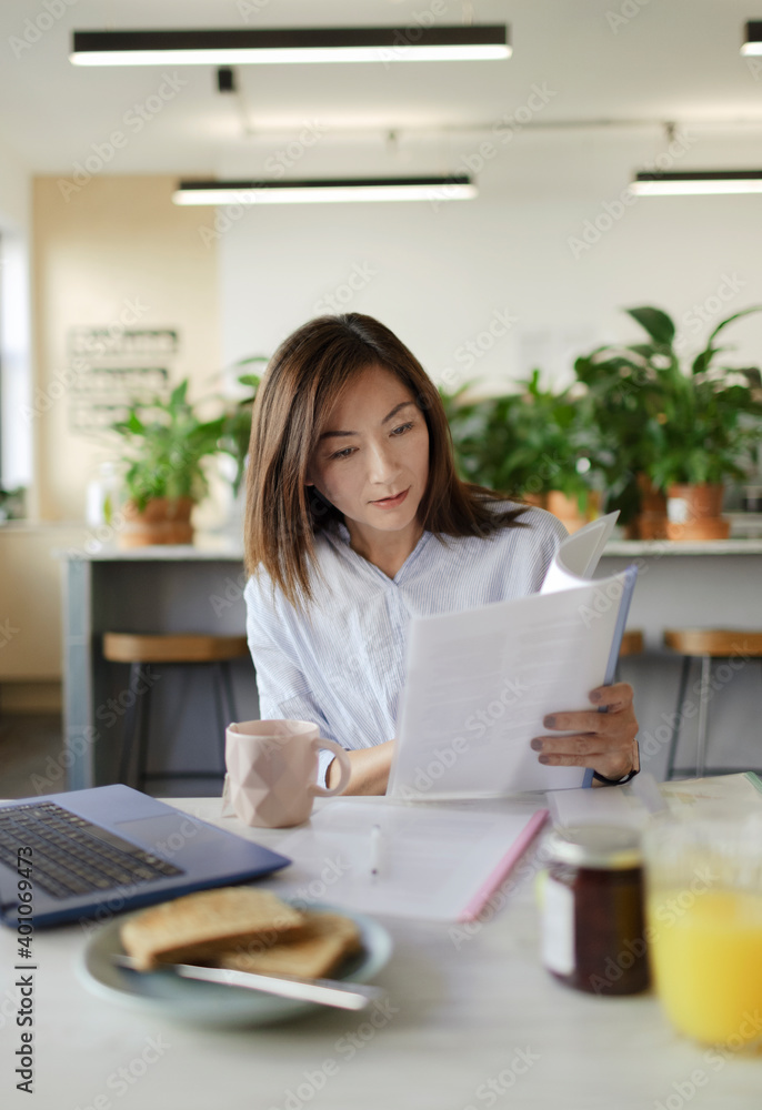 © Paul Bradbury/Caia Image - Businesswoman reviewing paperwork in office lounge