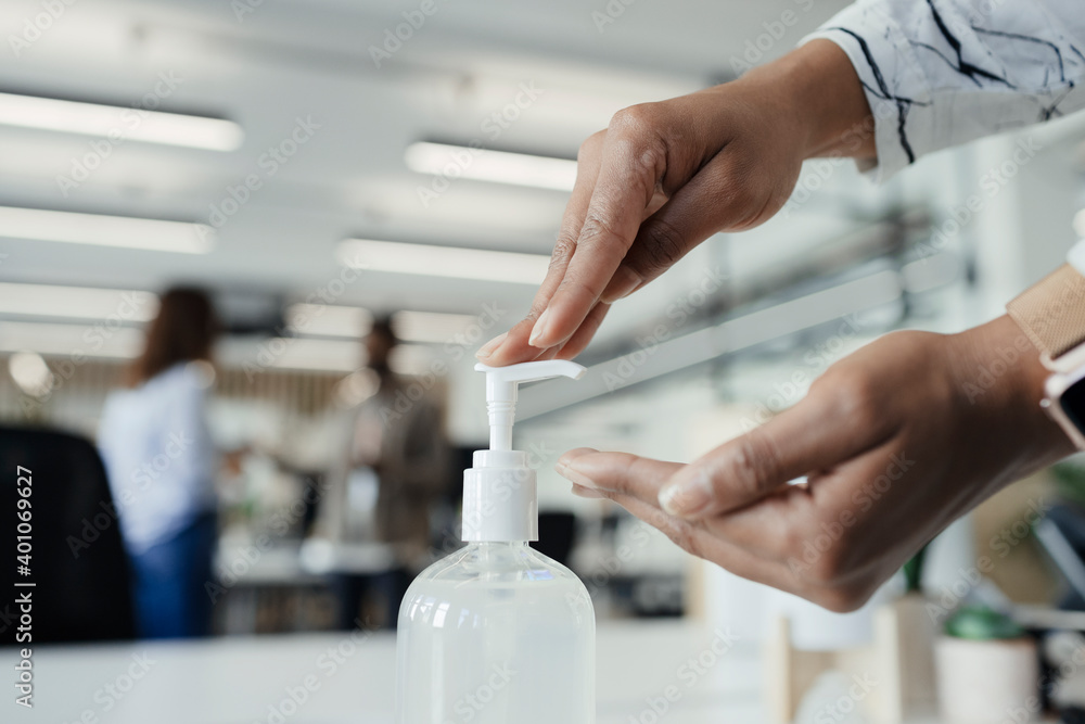 © Paul Bradbury/Caia Image - Close up businesswoman using hand sanitizer dispenser