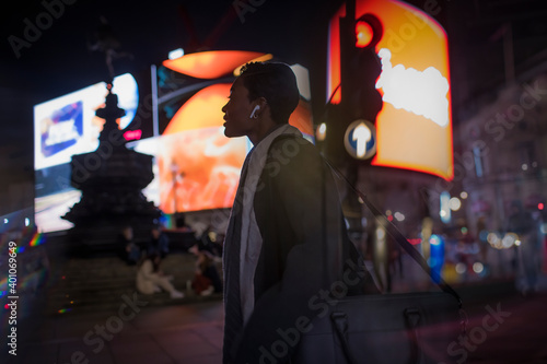 Young woman on city street corner at night, London, UK