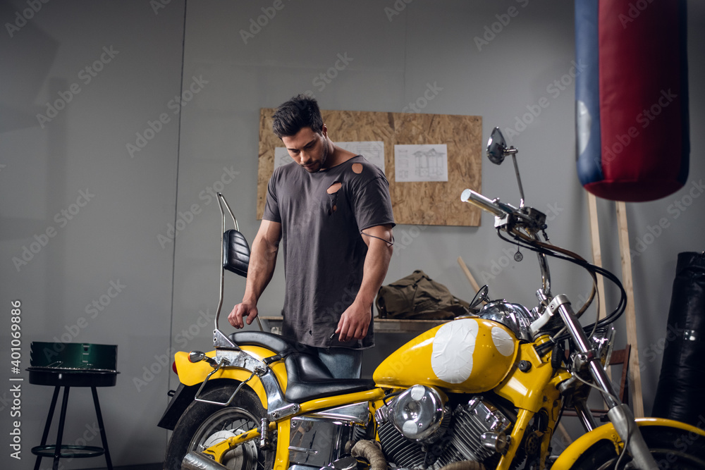 A young mechanic tuning a motorcycle in an auto repair shop. Hobbies and work activity