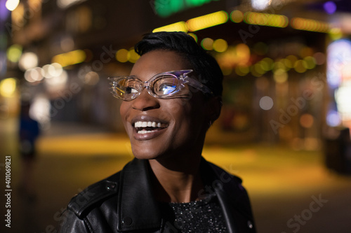 Happy young woman in funky glasses on city street at night photo