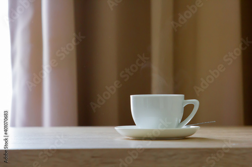 Coffee in white cup on wooden table in cafe with lighting background