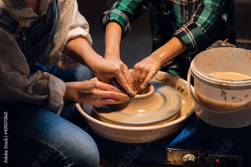 a young female potter teaches a small boy to make a pot of clay