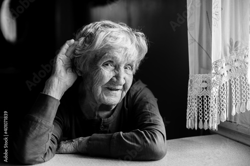 A hard-of-hearing old woman puts her hand to her ear. Black and white photo.