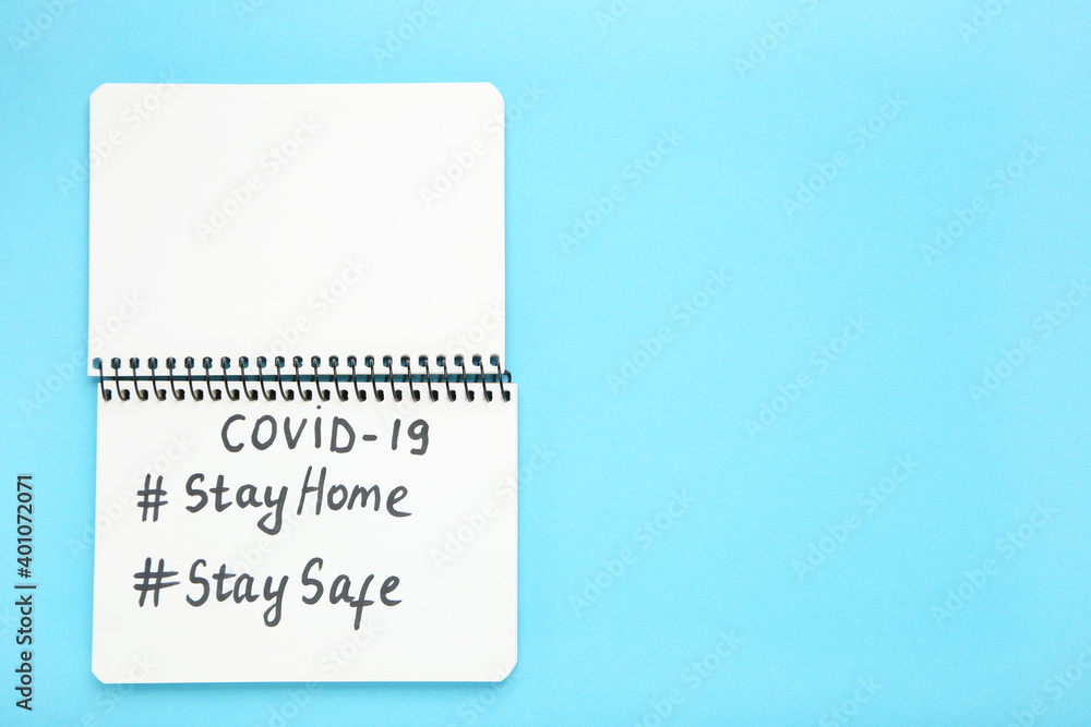Inscriptions Stay Home, Stay Safe, Covid-19. Notepad on blue background