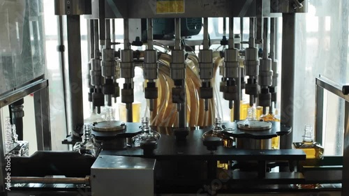 Machinery filling bottles with tequila on production line photo