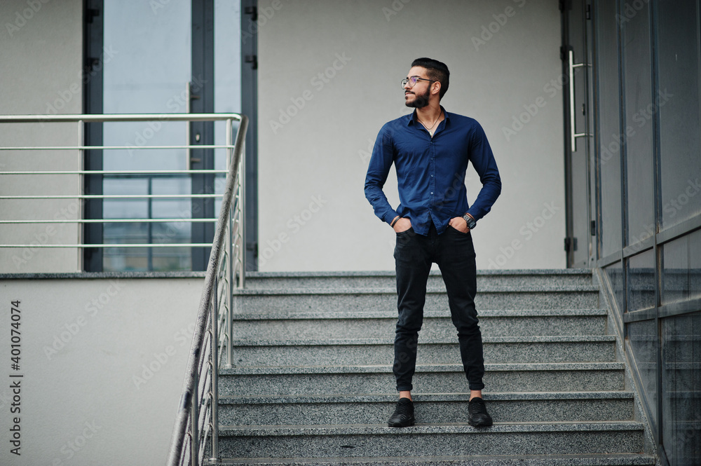 Middle eastern entrepreneur wear blue shirt, eyeglasses against office building. Middle eastern entrepreneur wear blue shirt, eyeglasses against office building.