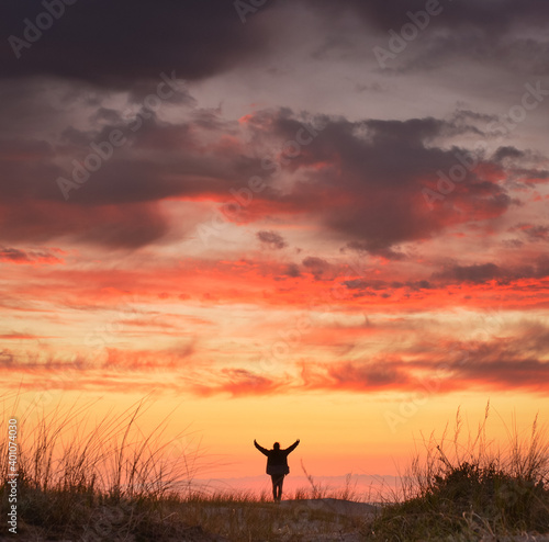 Woman beneath sunset sky