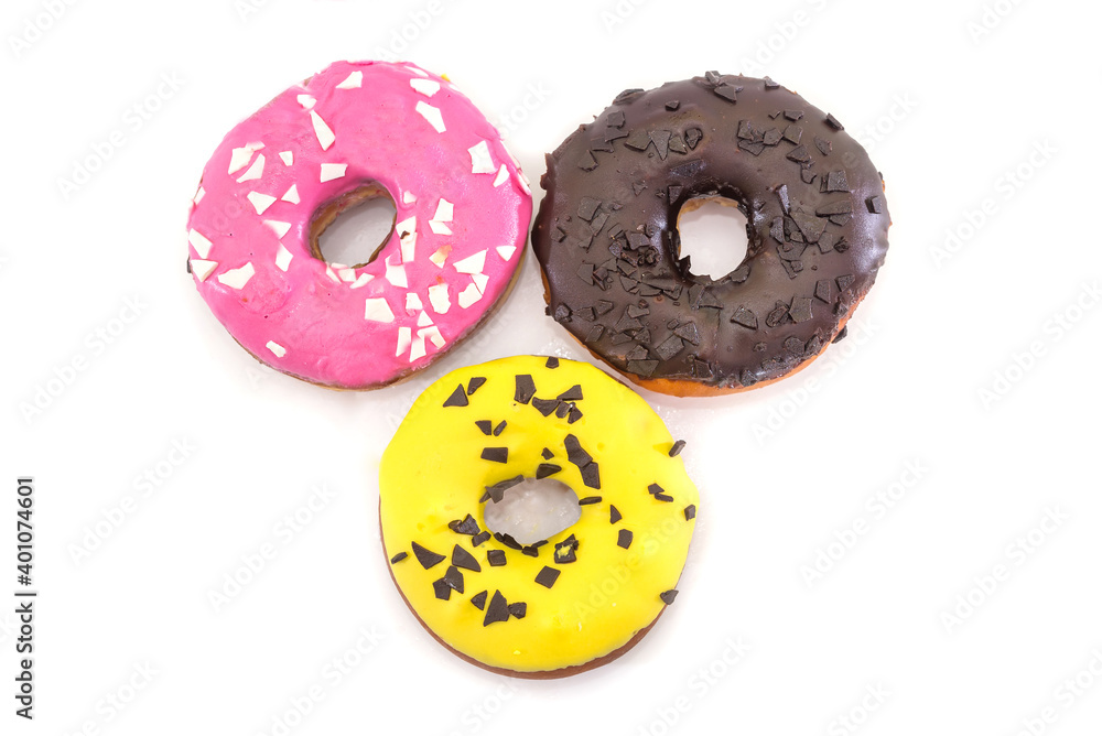 three traditional American donuts with chocolate, yellow, pink icing and sprinkles on a white plate. three traditional American donuts with chocolate, yellow, pink icing and sprinkles on a white plate.