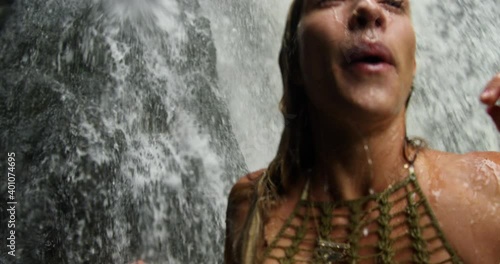 Smiling Caucasian woman standing under a waterfall photo