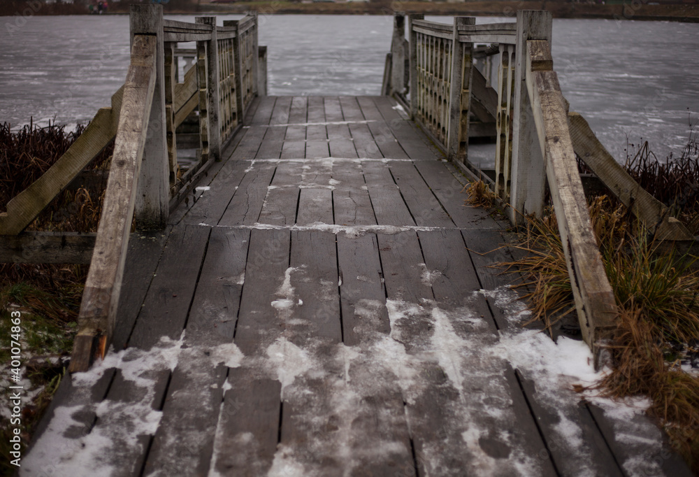 Obraz premium wooden pier on the frozen river Bank on a Sunny winter day