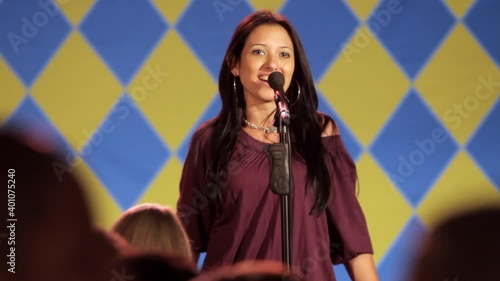 Woman on stage singing karaoke to crowd photo