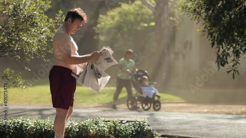 Shirtless man reading morning newspaper outdoors photo