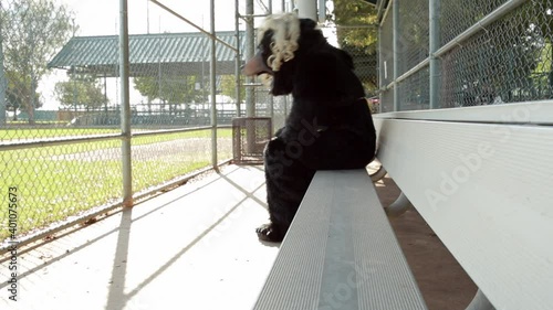 Caucasian man wearing bear costume removing mask in baseball dugout photo