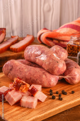 Raw brazilian bacon sausages on the wooden board with fresh cubes of bacon and spices - Linguiça de bacon