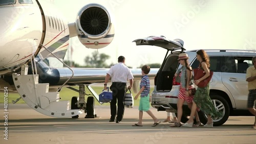 Caucasian pilot photographing family on tarmac near private jet photo