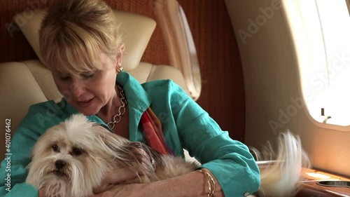 Caucasian woman on private jet hugging and kissing dog photo