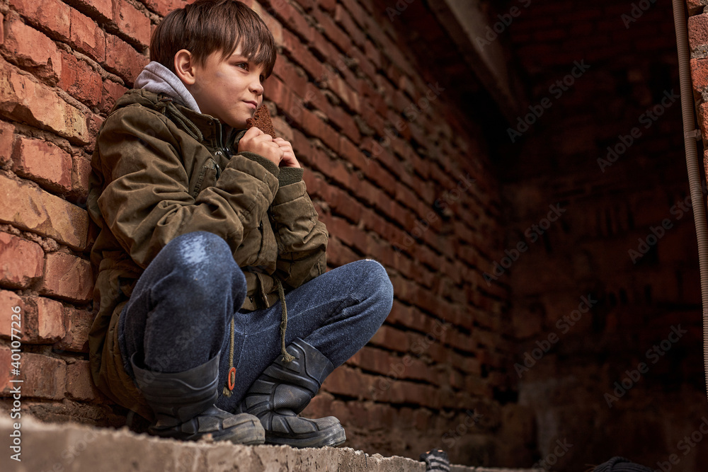 dirty and little homeless boy is begging in the buzy street, child look to the crowd with sad face hoping for sympathy. education is neglected to survive.