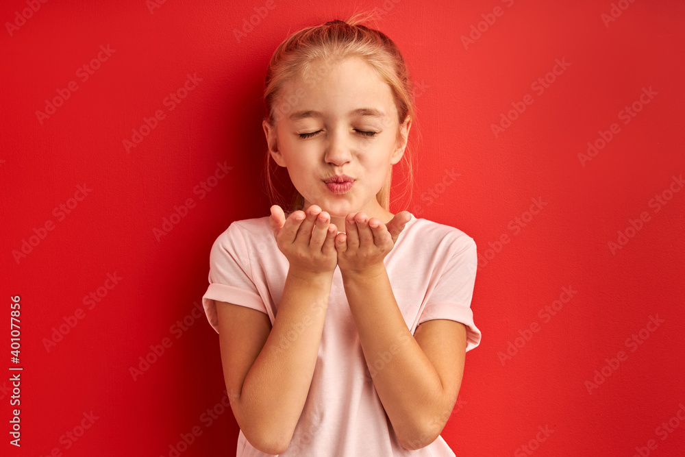 portrait of little girl sending blowing kiss at camera, expressing love emotions. isolated over red background portrait of little girl sending blowing kiss at camera, expressing love emotions. isolated over red background