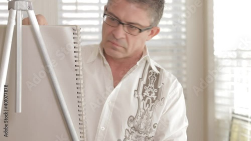 Mixed race man sketching at easel photo