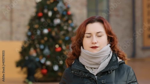 Wallpaper Mural Serious young redhead woman standing in front of christmas tree outdoors Torontodigital.ca