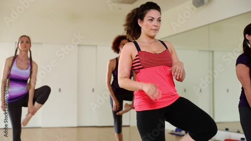 Woman struggling with yoga pose during yoga class in studio photo