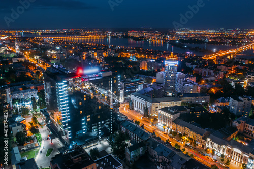 Aerial view night city with illuminated roads, streets and modern buildings in downtown at night dusk.